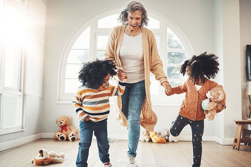 A woman practices maintaining good balance by exercising with her grandchildren.