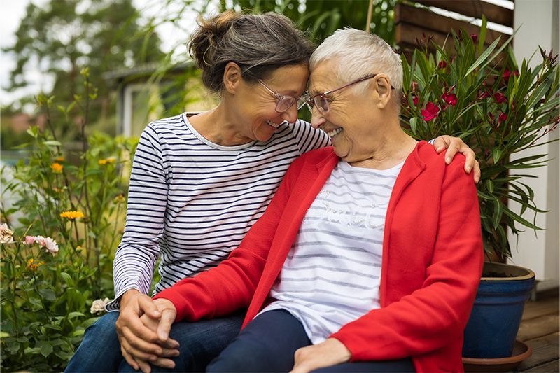 A caregiver holds the hand of her senior client, showcasing creative Alzheimer’s communication strat
