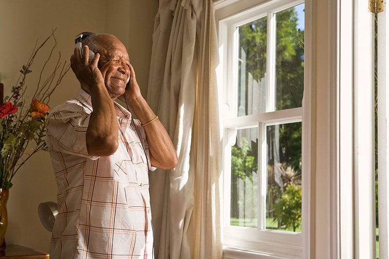 A man with mobility problems in Parkinson’s smiles as he listens to music.