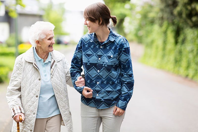 A woman who understands why seniors are falling more often and how to help, links arms with her mother to increase her balance and stability.