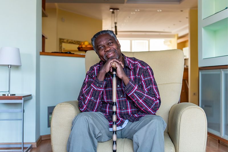 A man leans on his cane as he prepares to stand up, understanding the risks of prolonged sitting for