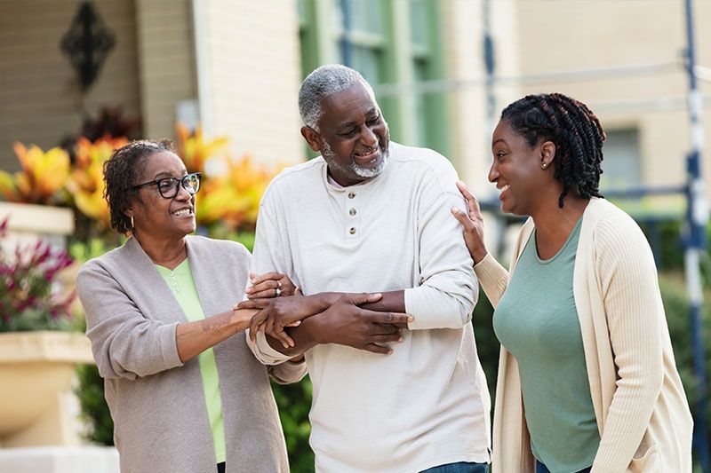 A woman walks alongside her elderly mom and dad, balancing care for two parents.