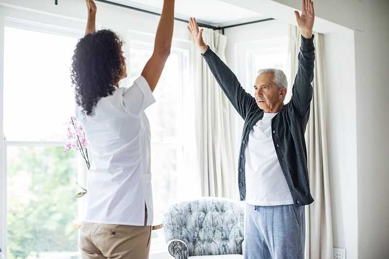 An older man practices mind-body movements with his caregiver to reduce frailty and build resistance