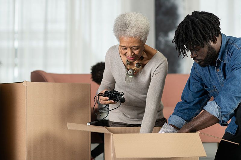 A man who knows the best strategies for downsizing your parents’ home helps his mom pack up boxes.