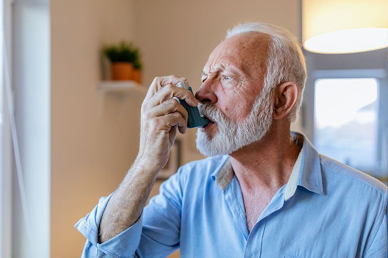 A man uses an inhaler to help with health concerns related to COPD.