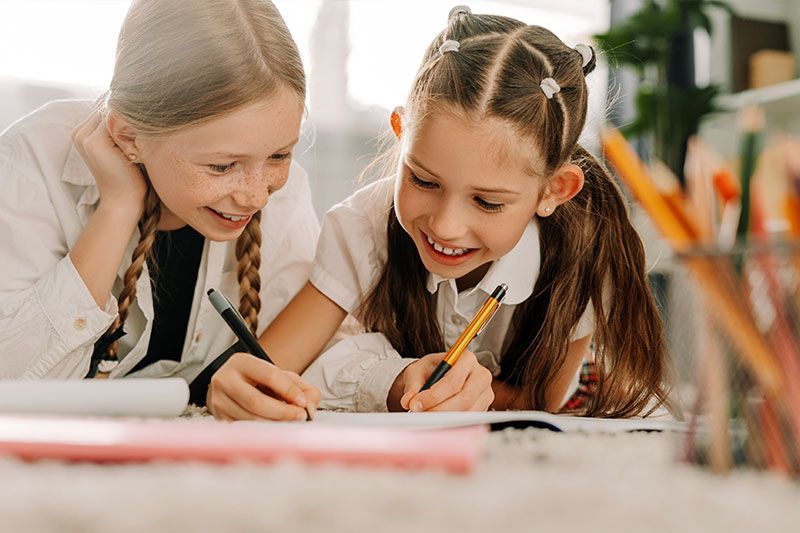Two girls laugh as they write a letter to their grandparent, who had been wondering how to engage more with grandkids.