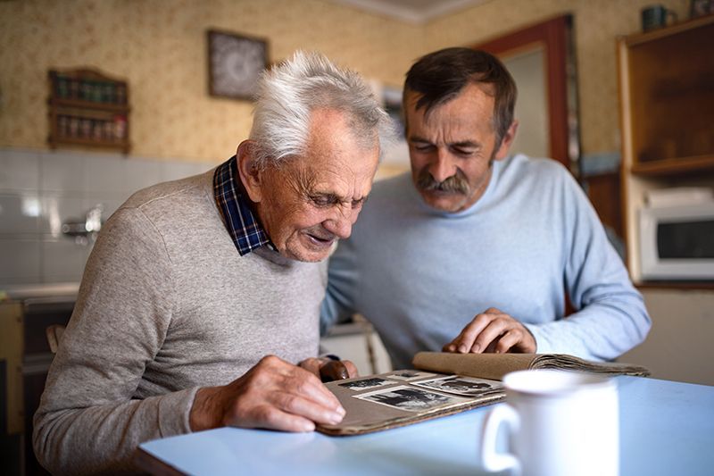 A man uses reminiscence therapy for dementia with his dad as they look at a photo album together.