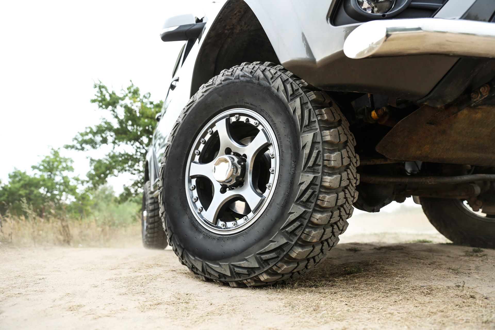 Mud tire close-up on SUV, highlighting truck parts and accessories in summer outdoor environment.
