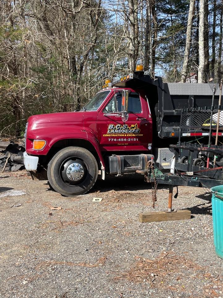 Red dump truck parked outdoors on gravel.