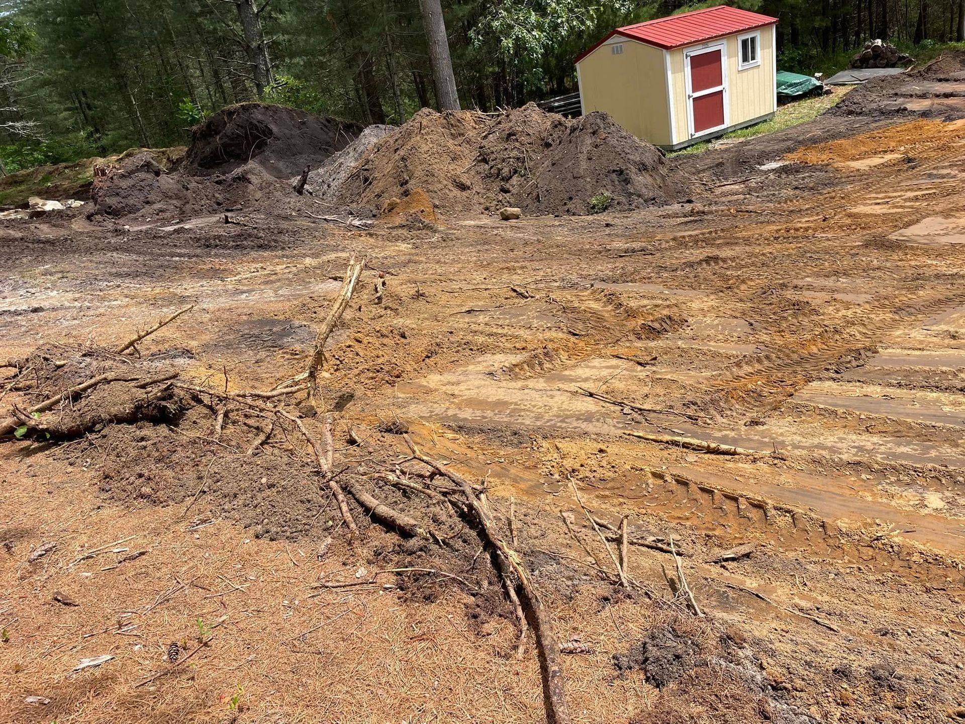 Dirt and mud field with a small shed in the background. Piles of dirt on the left.