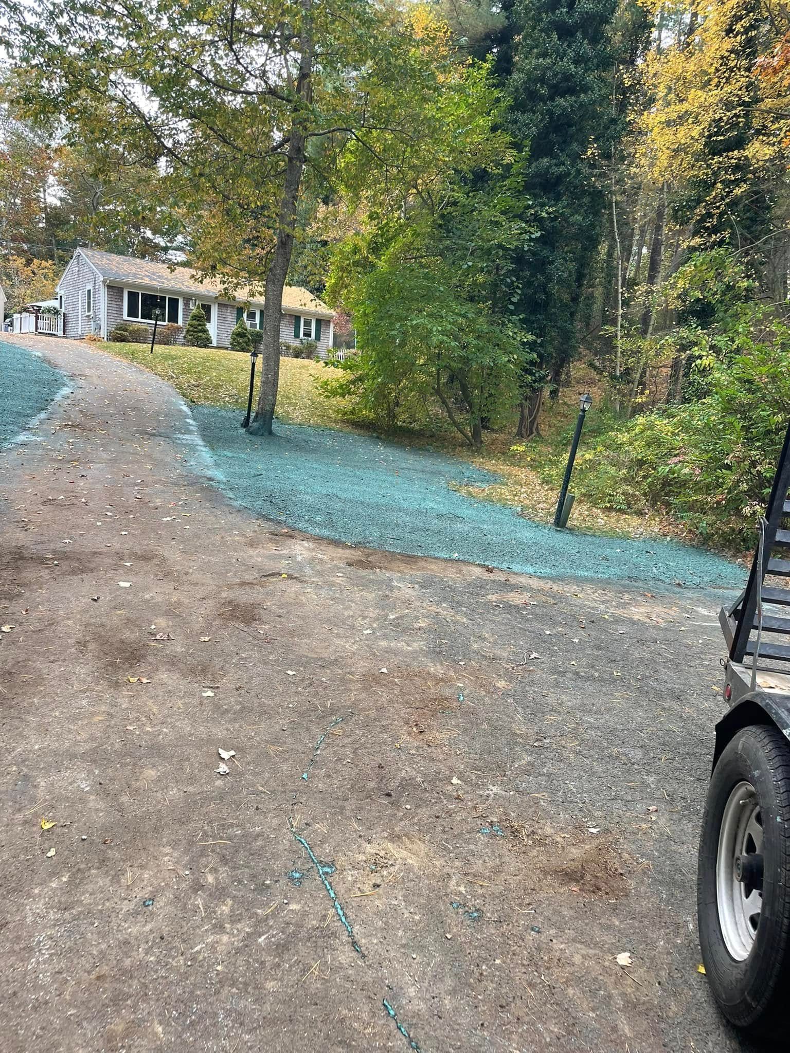 Driveway with newly seeded grass; house in background, right side of a vehicle.