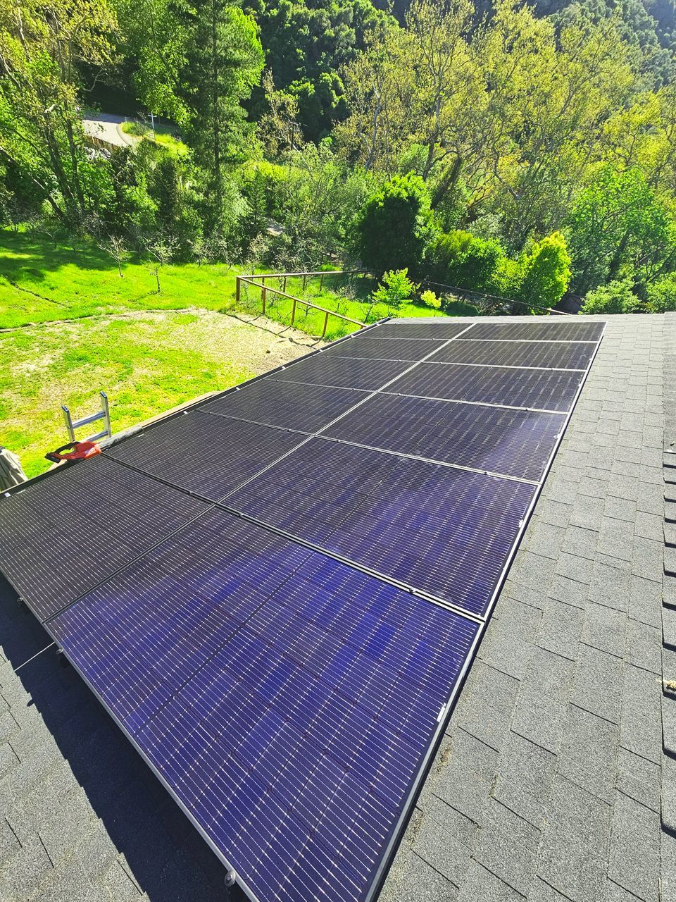 Solar panels installed on a rooftop overlooking a green hillside.