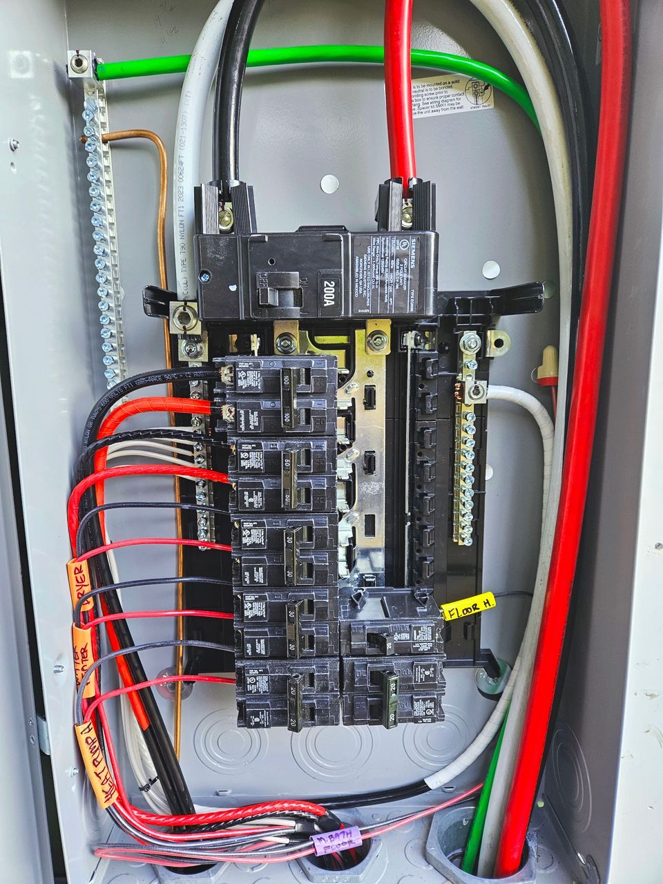 Electrical panel with various colored wires and circuit breakers.