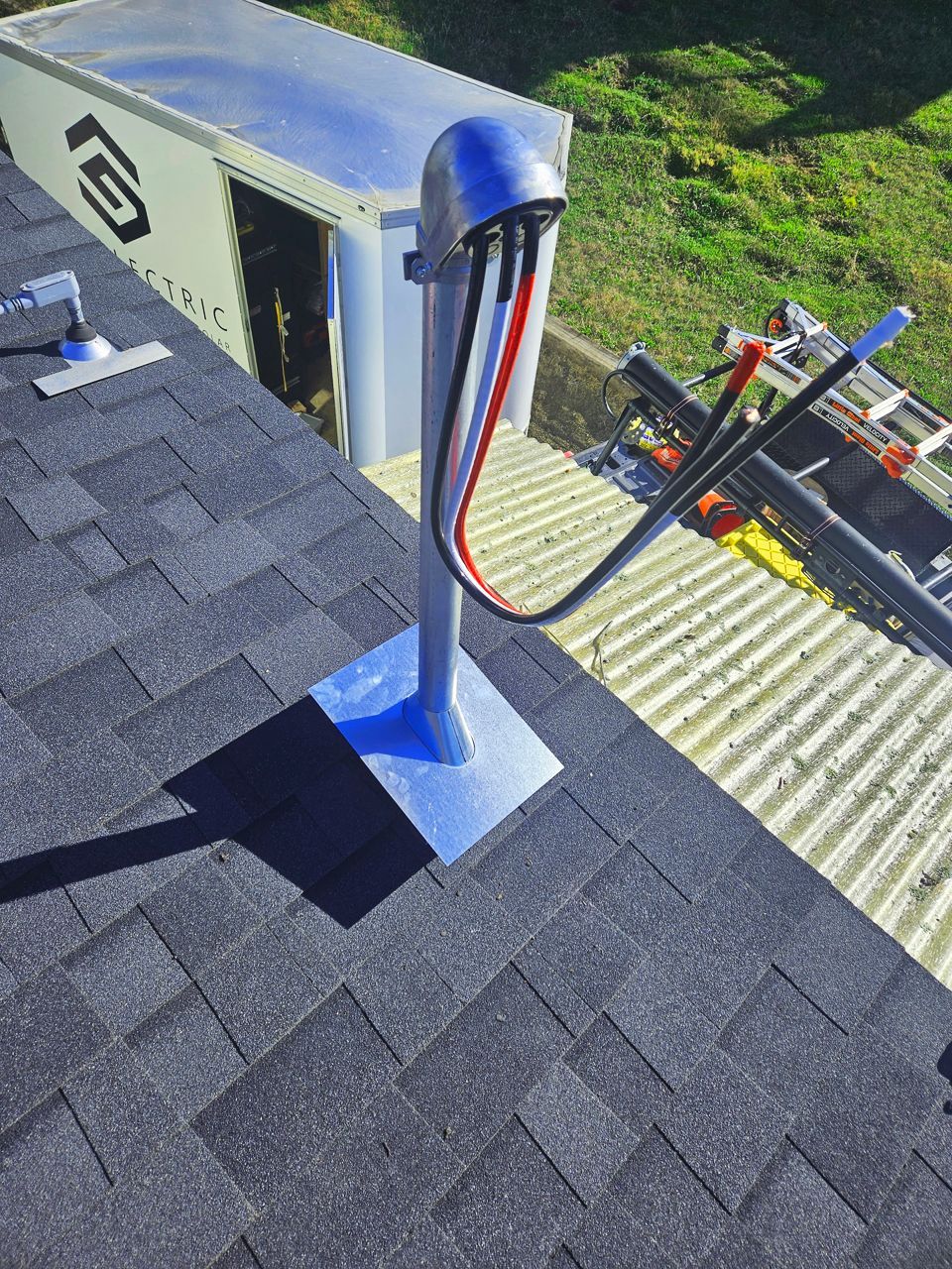 Electrical conduit on a rooftop, with black, red, and white wires. Silver metal base and cover.