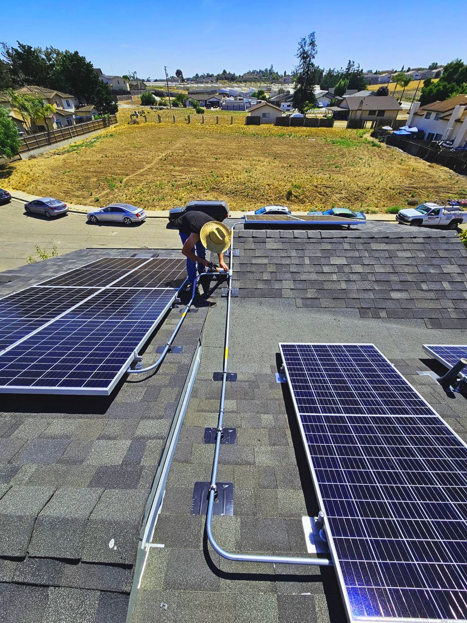 Solar panels being installed on a roof, workers on a rooftop on a sunny day.