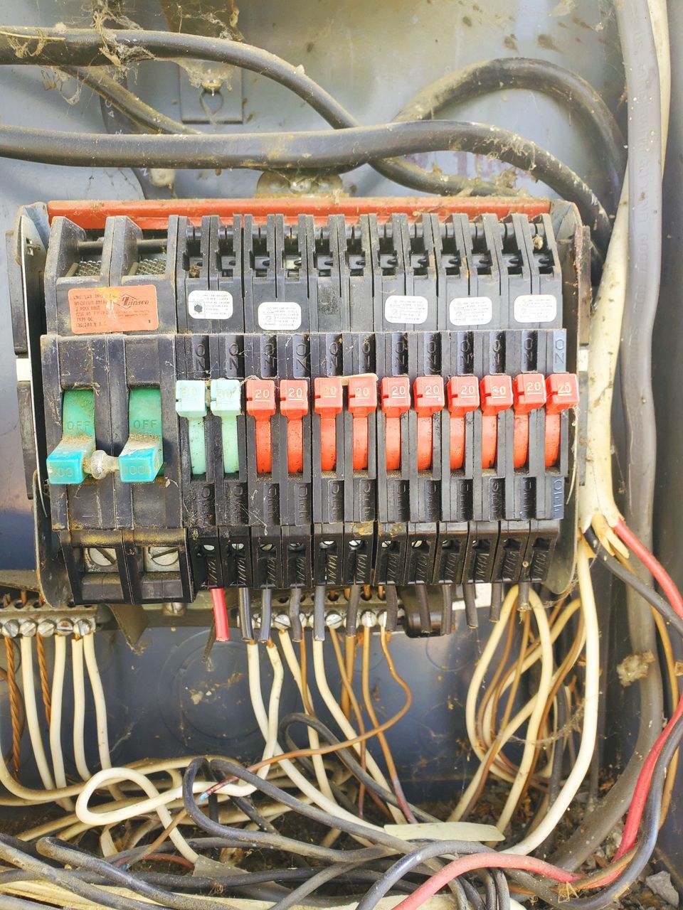Electrical breaker panel with various colored switches and exposed wires.