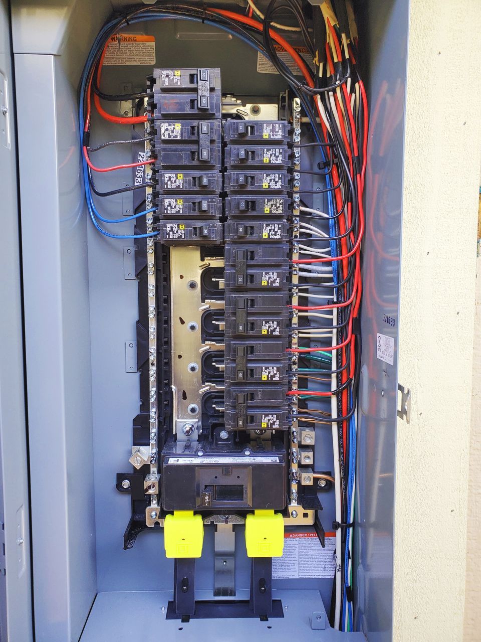 Electrical panel with circuit breakers and wires.