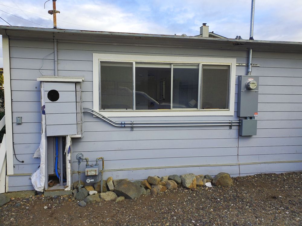 Light blue building exterior with a window, electrical panel, and utility box.
