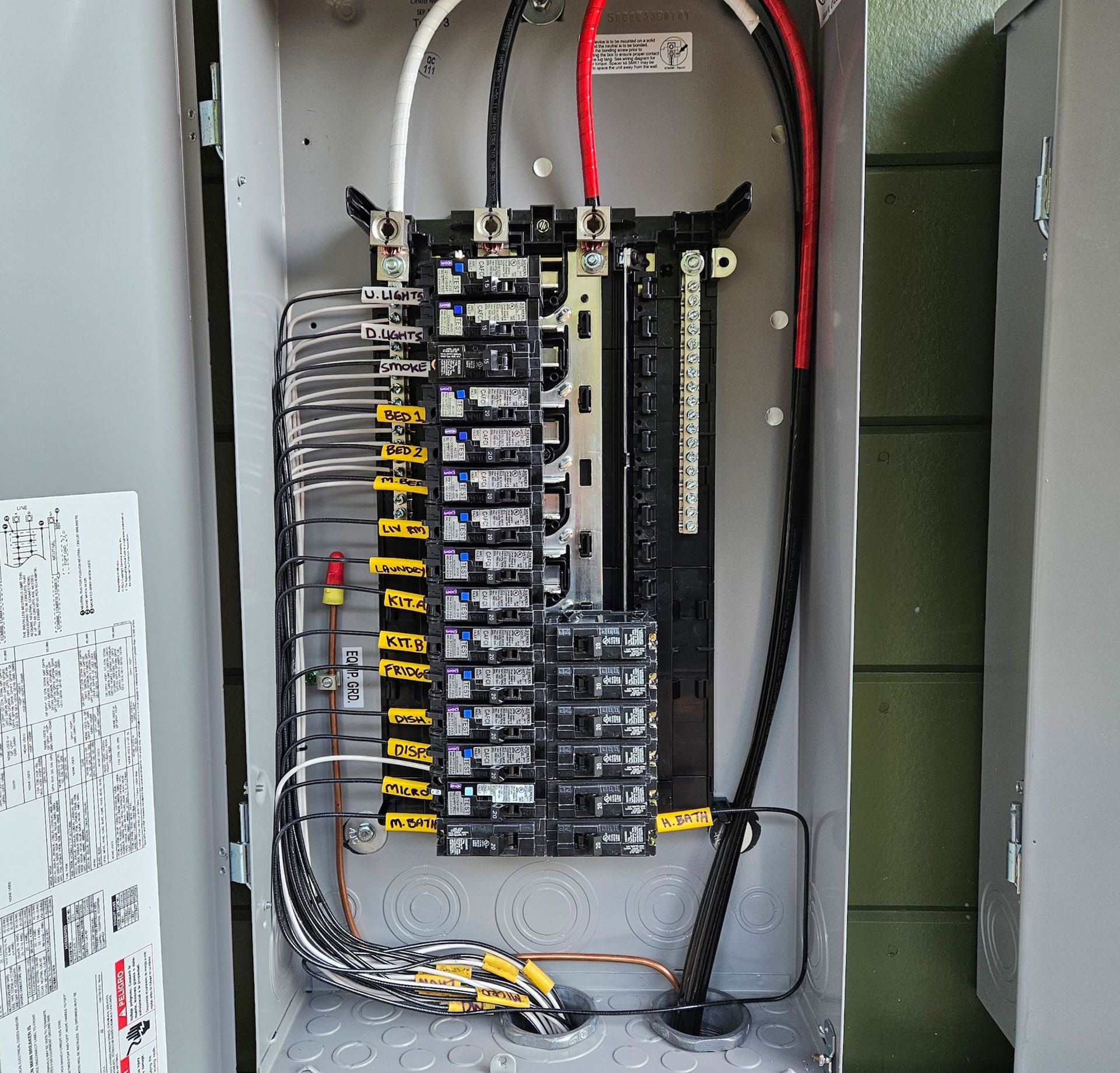 Open electrical panel with wires and circuit breakers.