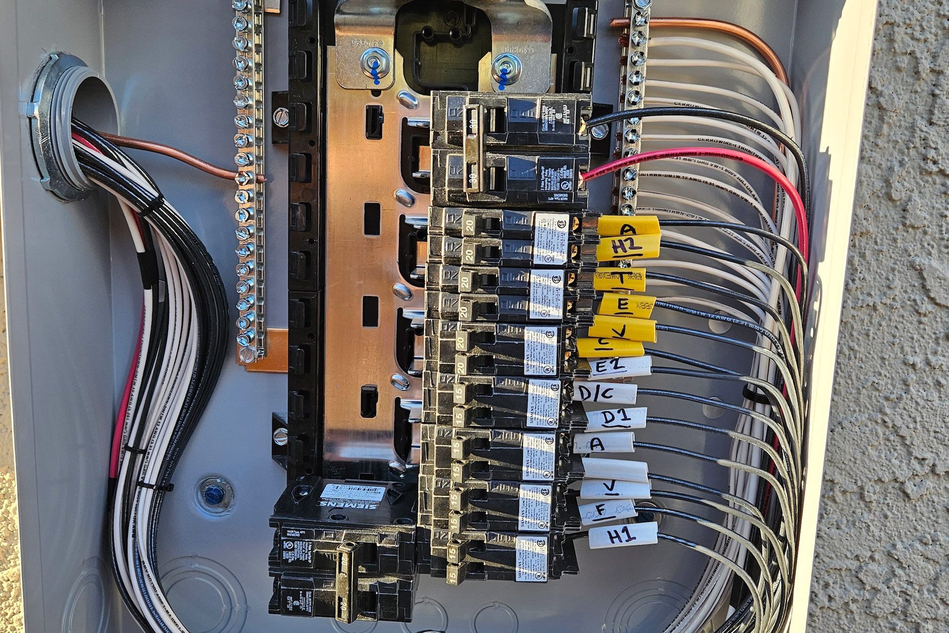 Electrical panel with labeled circuit breakers and wires. Copper grounding bar visible.
