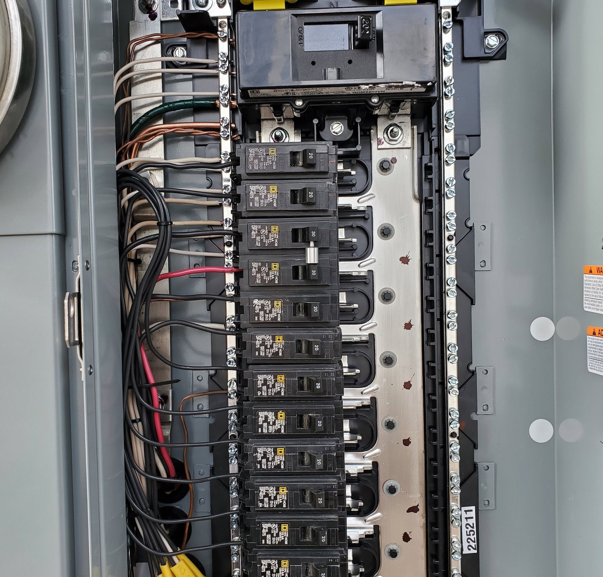 Electrical panel with rows of circuit breakers and wiring.