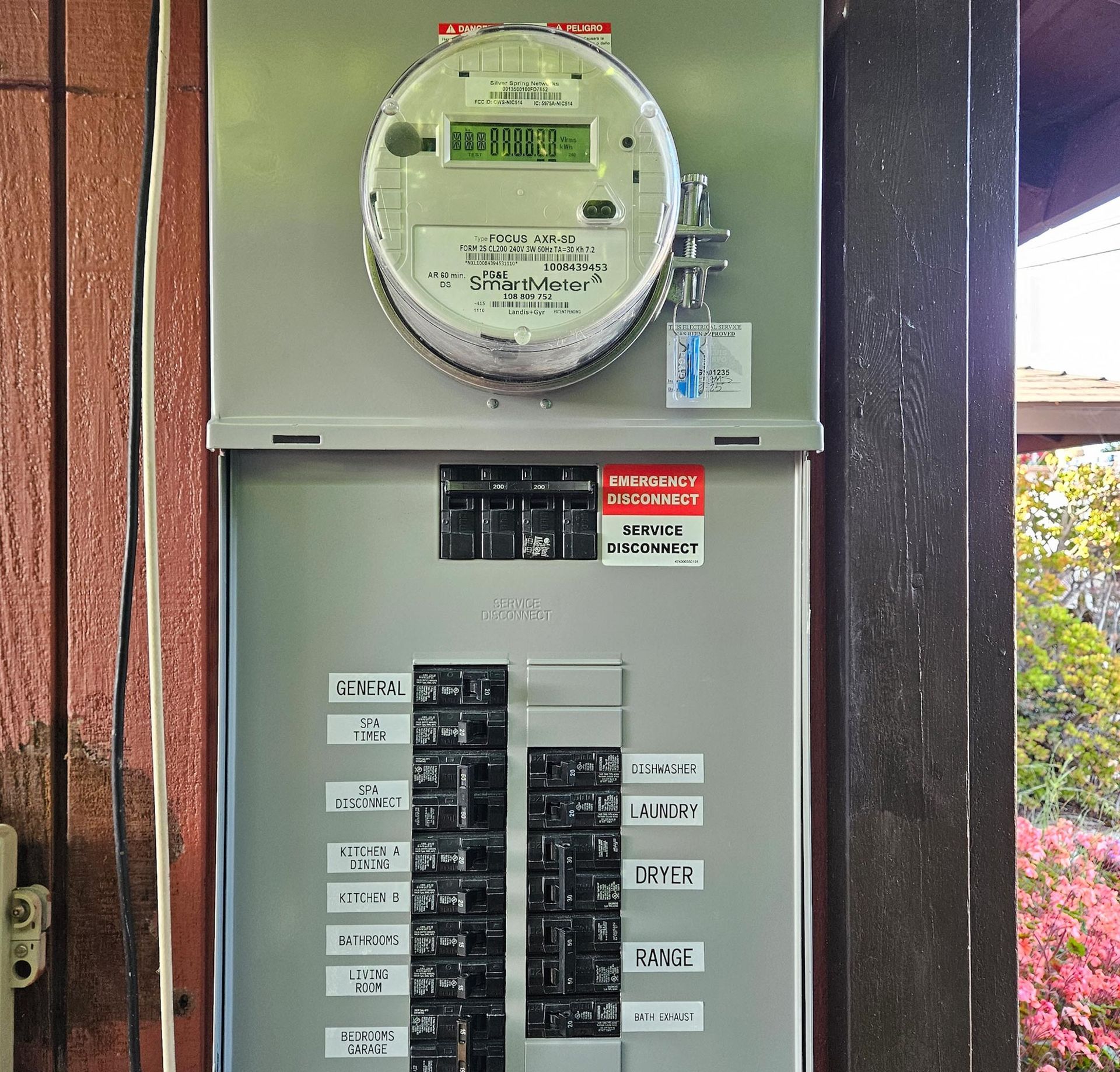 Electric meter and circuit breaker panel on a wooden exterior wall.