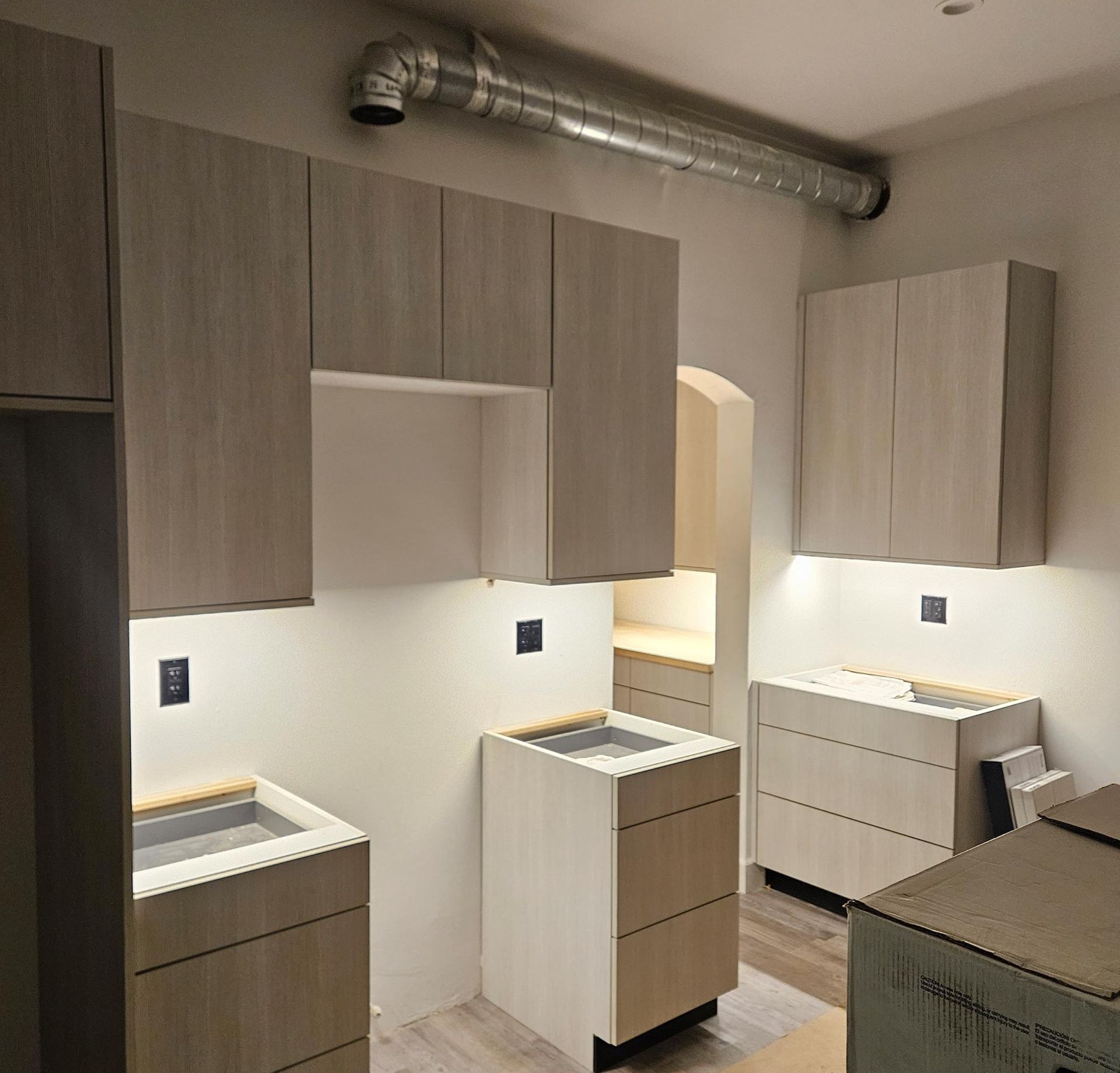 Newly installed modern kitchen cabinets with under-cabinet lighting.