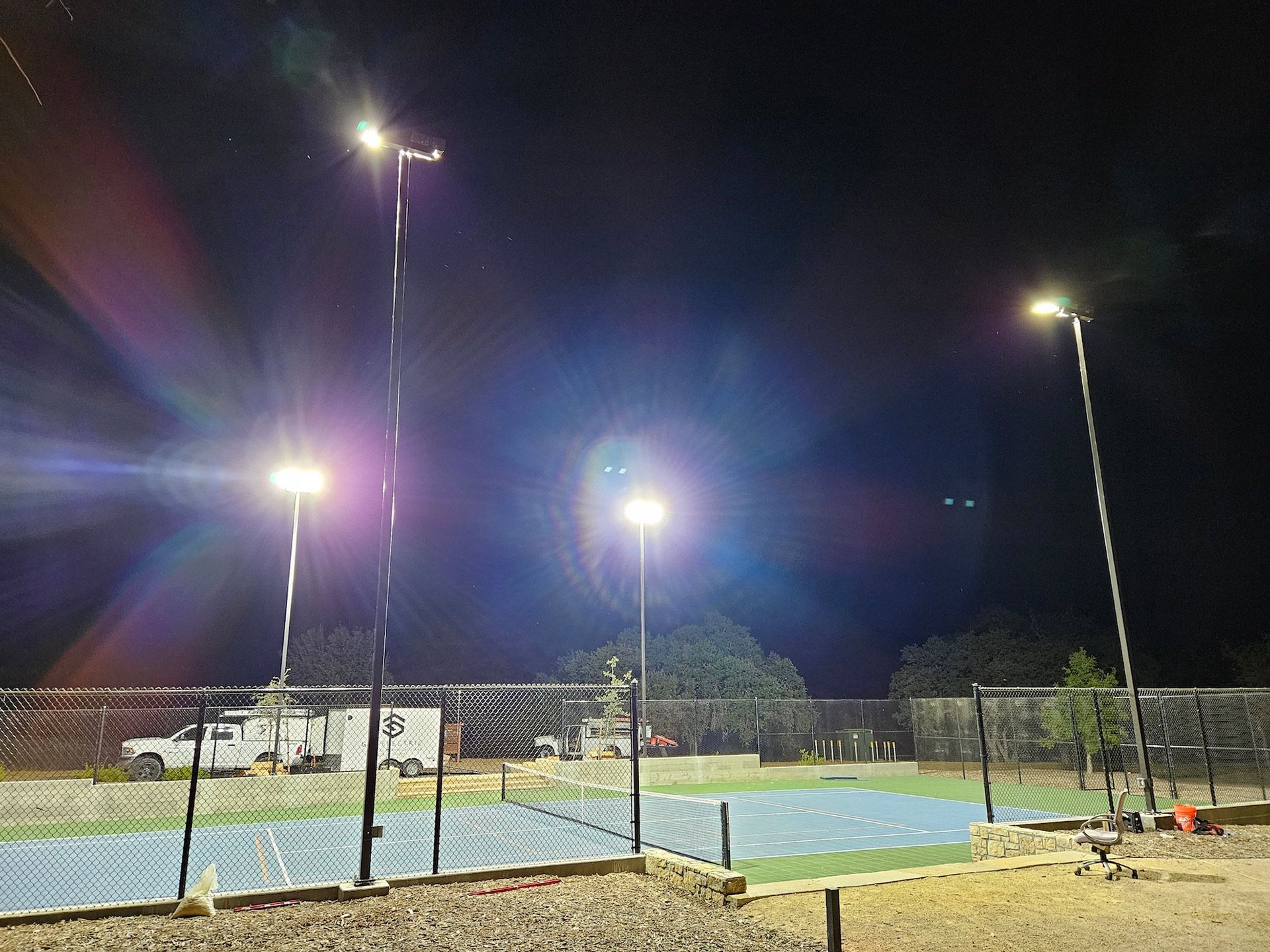 Outdoor pickleball court lit by bright overhead lights at night.