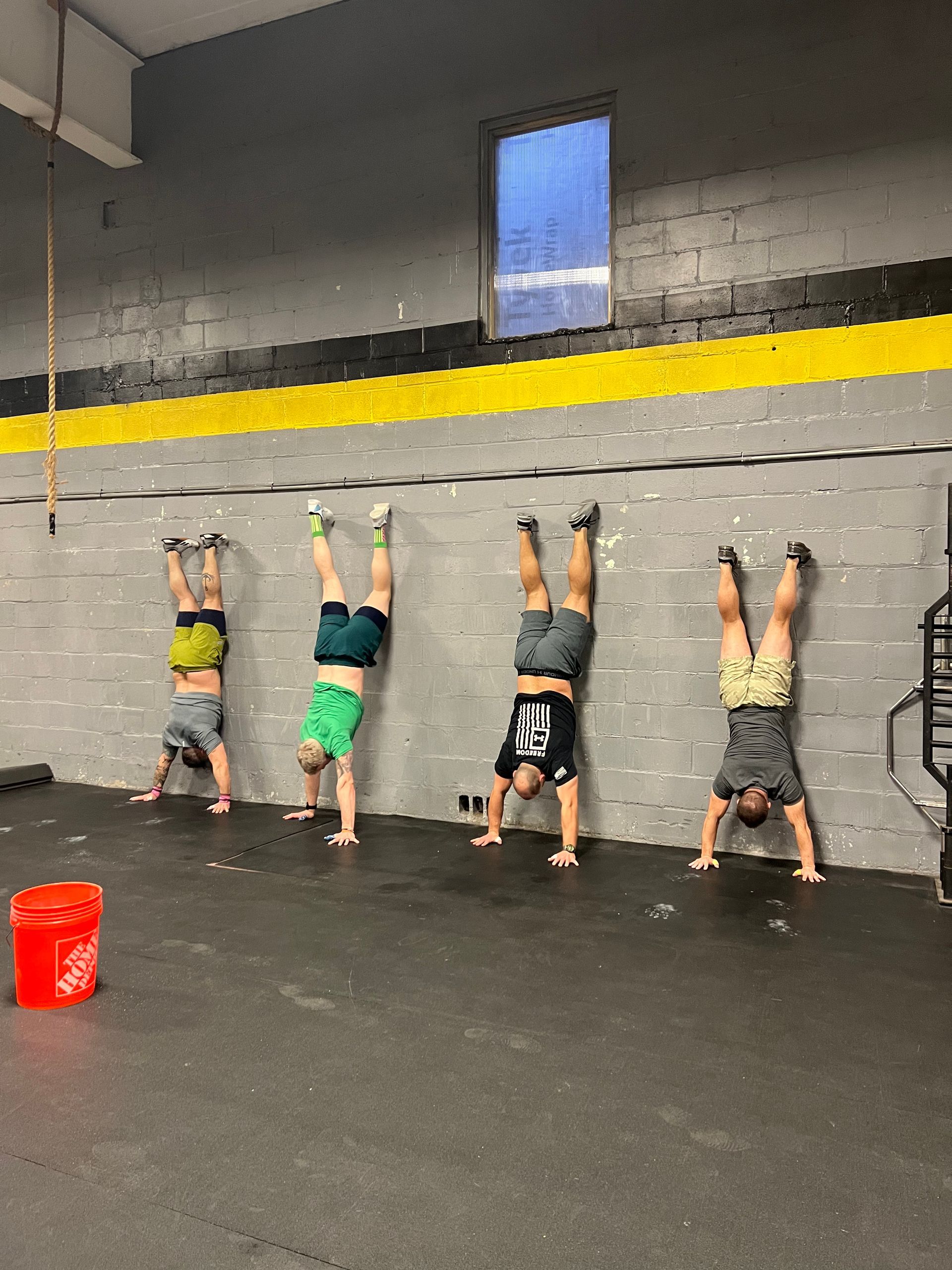A group of people are doing handstands in a gym.