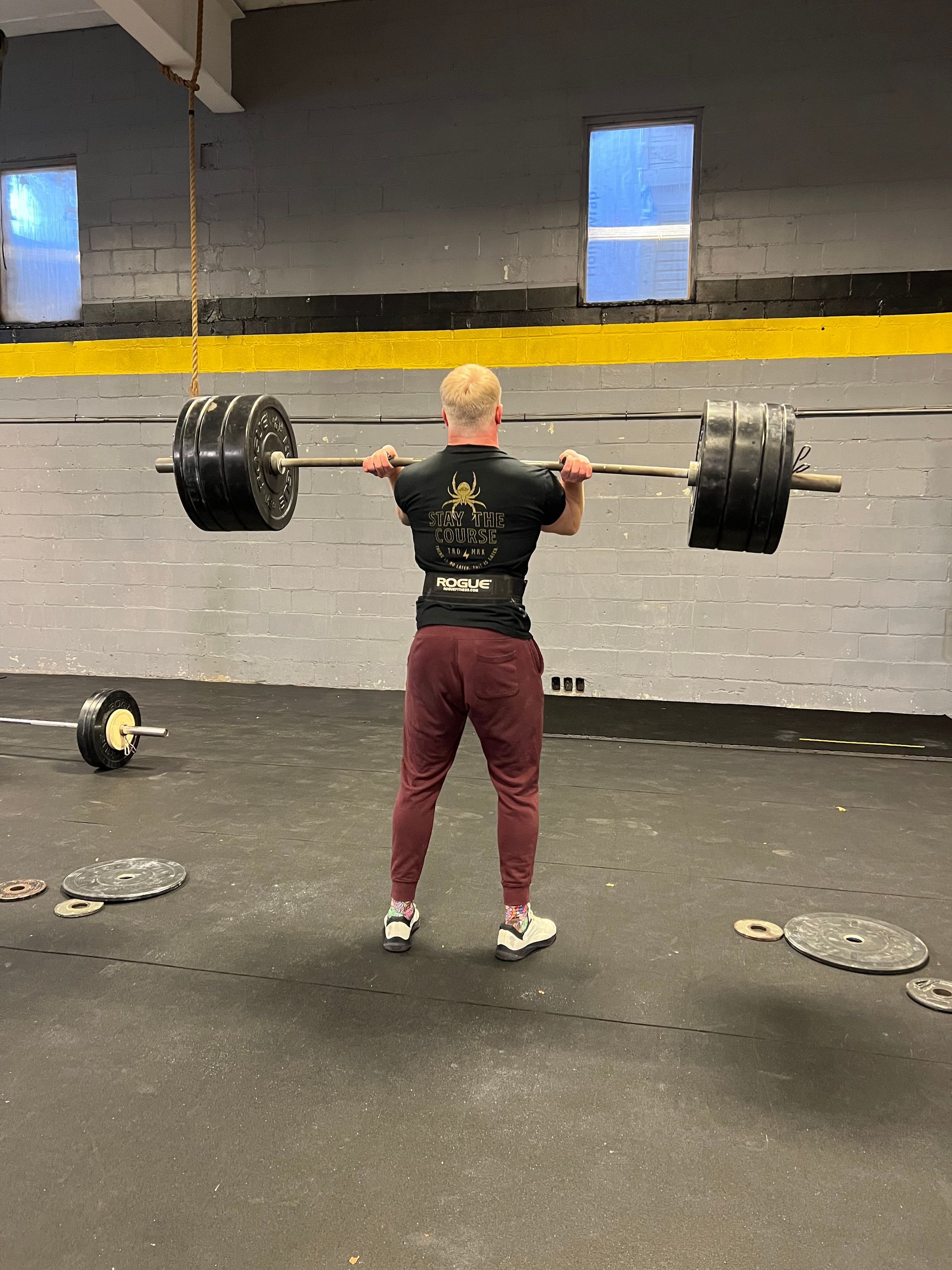 A man is holding a barbell over his head in a gym.