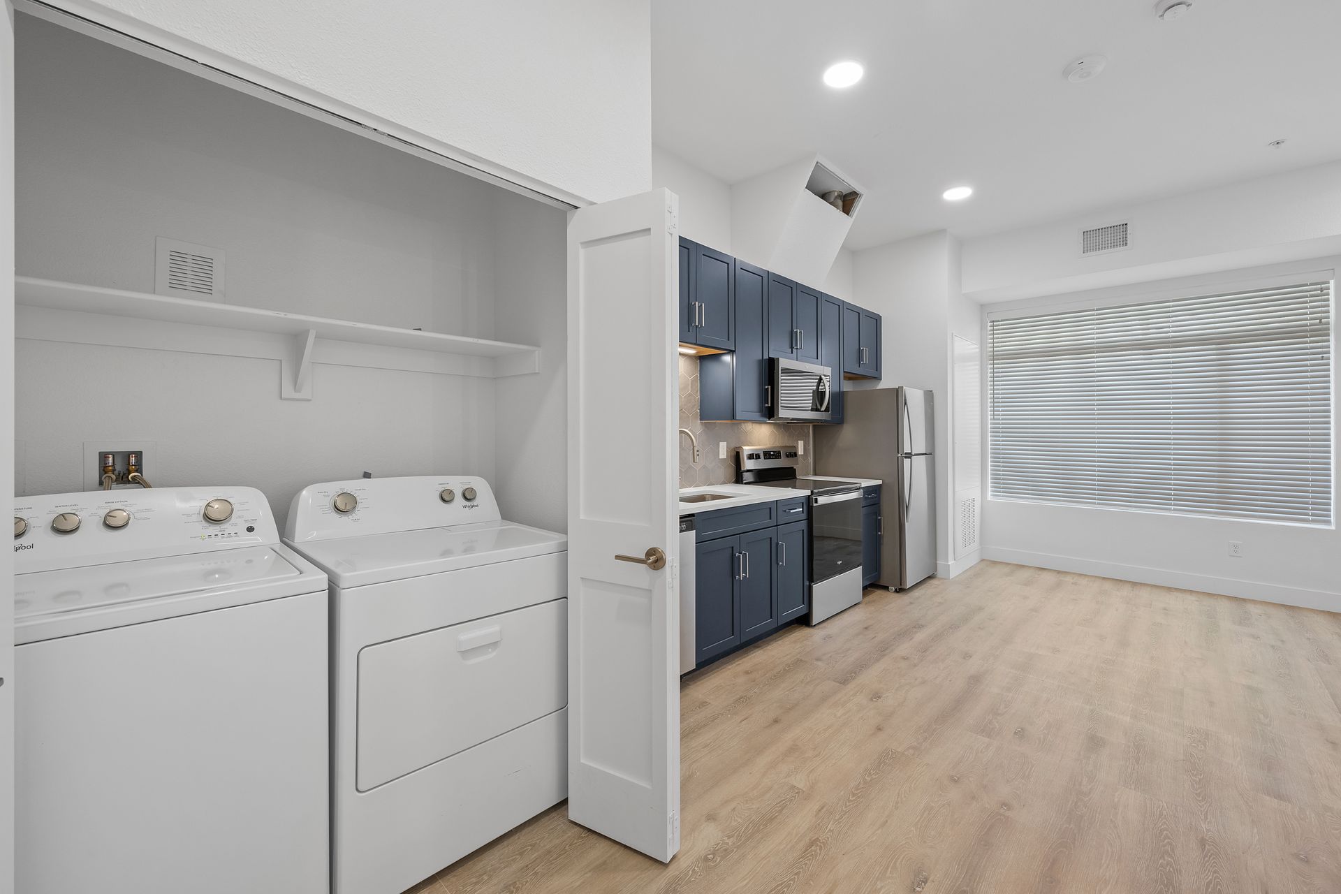 photo showing laundry area with the kitchen in the background - studio floor plan likely