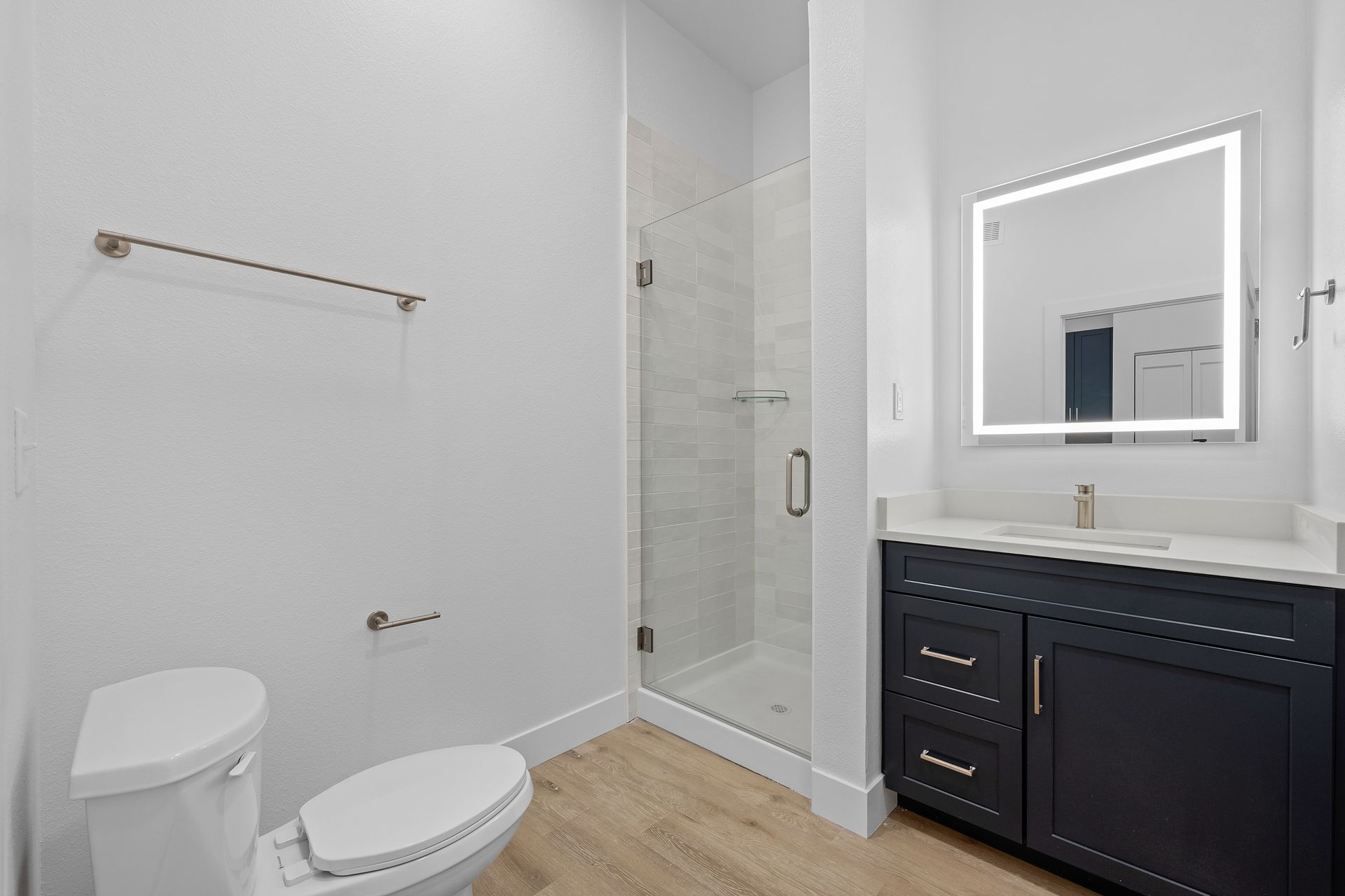 photo showing a bathroom with a shower with a glass door and mirror with vanity lighting