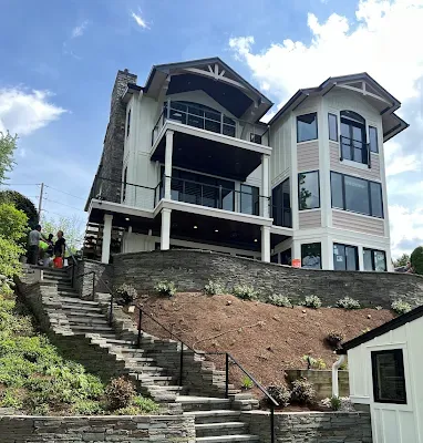 White house with blue door and garage, gray roof, lawn and concrete driveway.