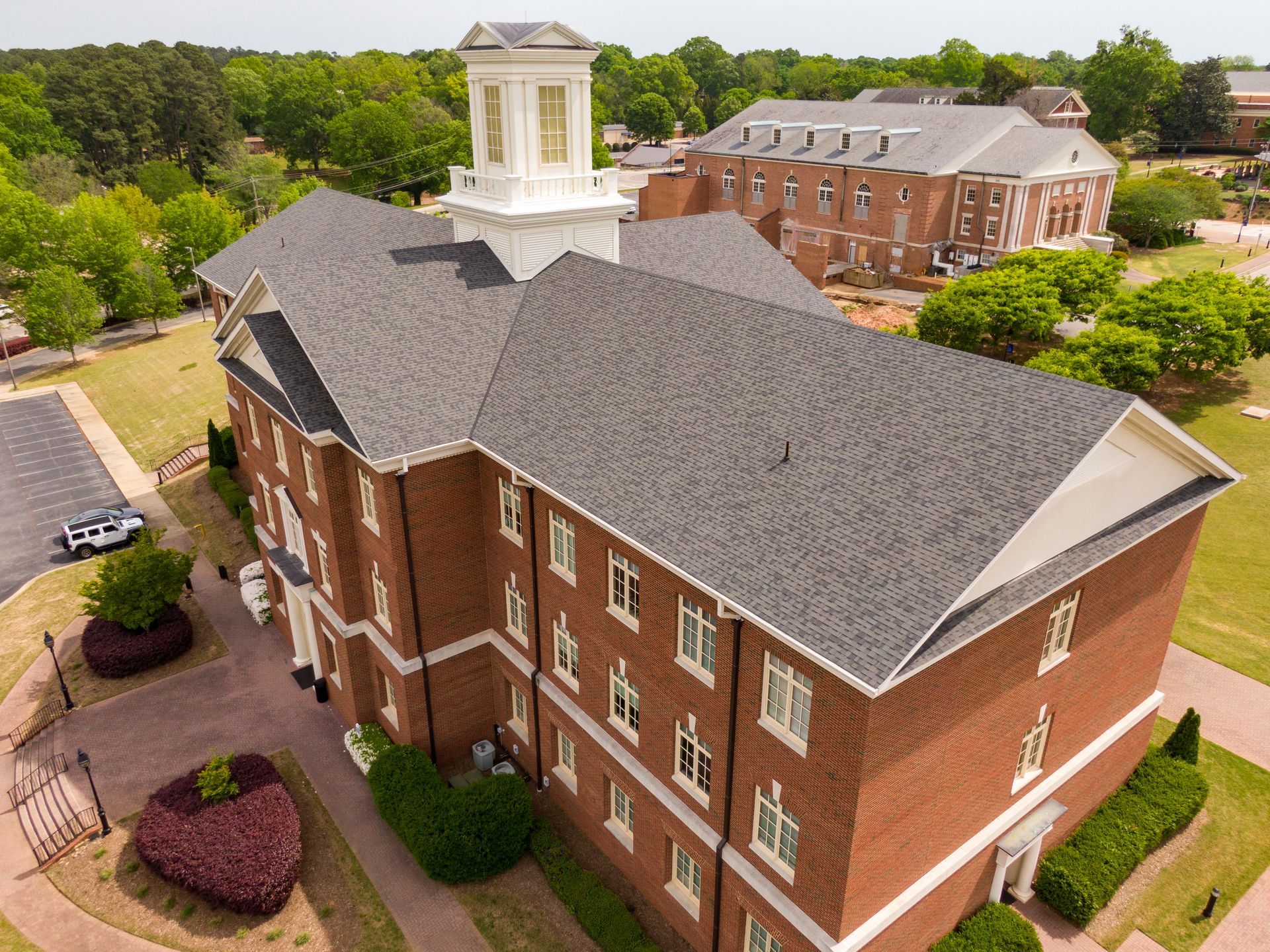 Brick building with a cupola on a college campus, surrounded by greenery and other buildings. Brick building with a cupola on a college campus, surrounded by greenery and other buildings.