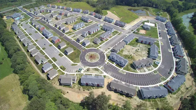 Gray house with a dark gray shingled roof, light gray siding, and two garage doors against a blue sky.