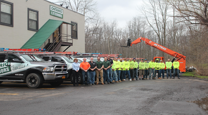 Beige two-story house with white trim, red door, black shutters, and a covered porch.