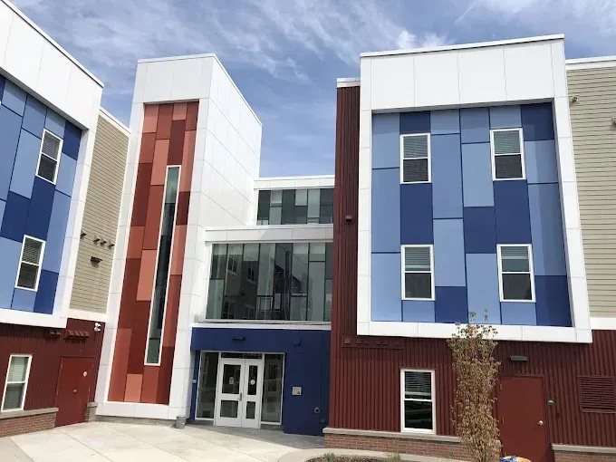 Gray two-story house with a driveway and green lawn on a sunny day.