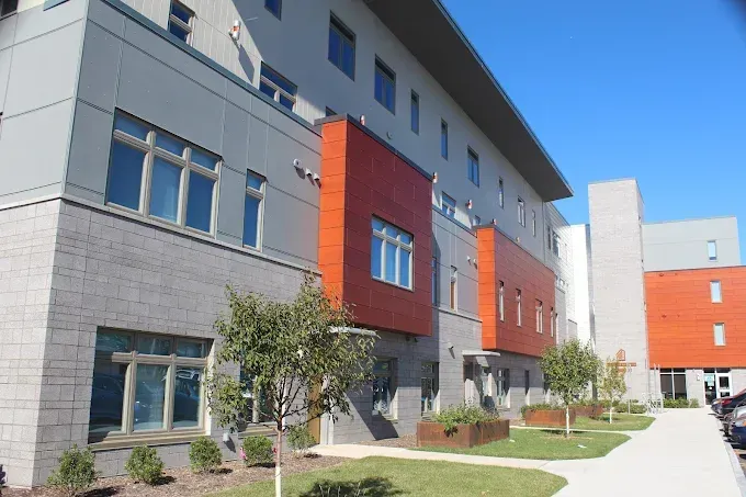 Two-story industrial building with brick facade, brown trim, and multiple rectangular windows under a blue sky. Two-story industrial building with brick facade, brown trim, and multiple rectangular windows under a blue sky.