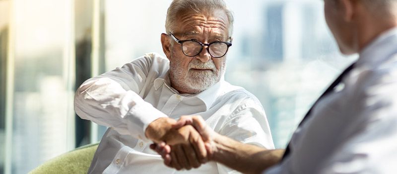 older man shaking hands with younger man in committment