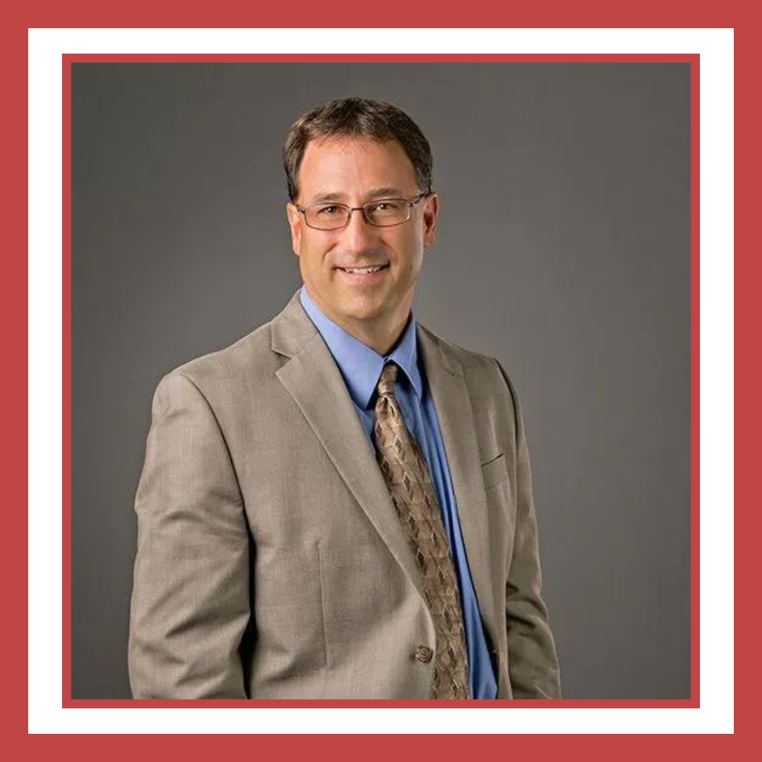 A man in a suit and tie is smiling for the camera.