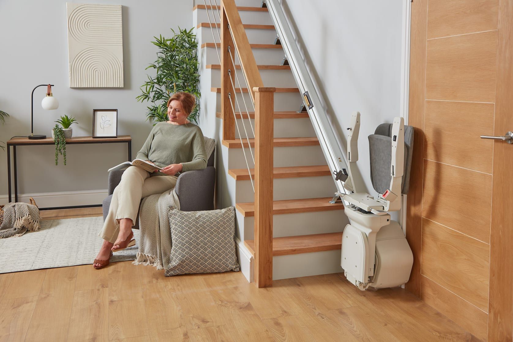 Woman seated beside a staircase lift in a bright living room