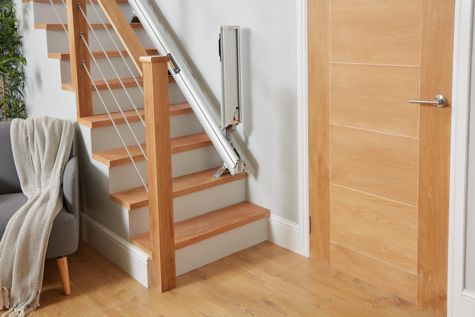 Staircase with wooden steps, metal railing, and a closed wooden door in a bright home interior