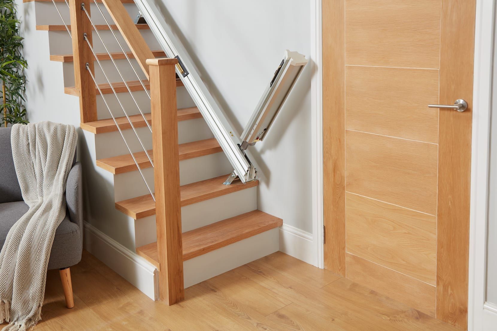 Indoor staircase with a chairlift beside wooden stairs and a closed door on the right