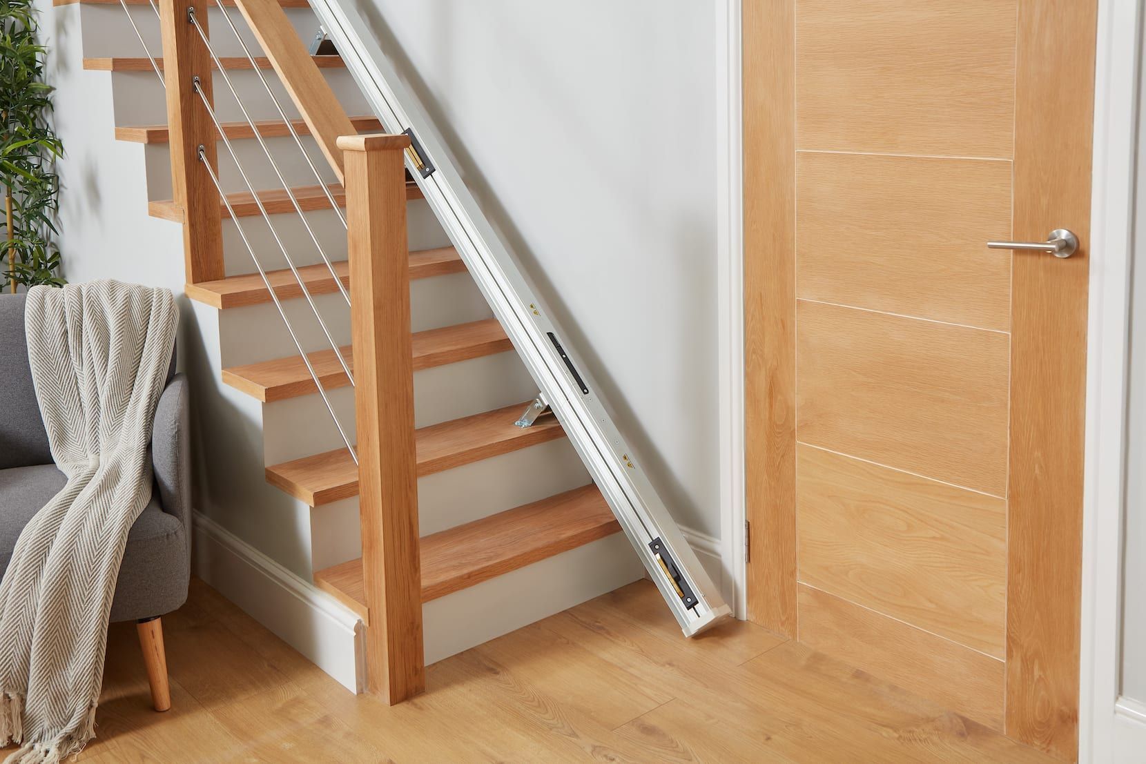 Wooden staircase in a home with a metal handrail and a closed light wood door beside it