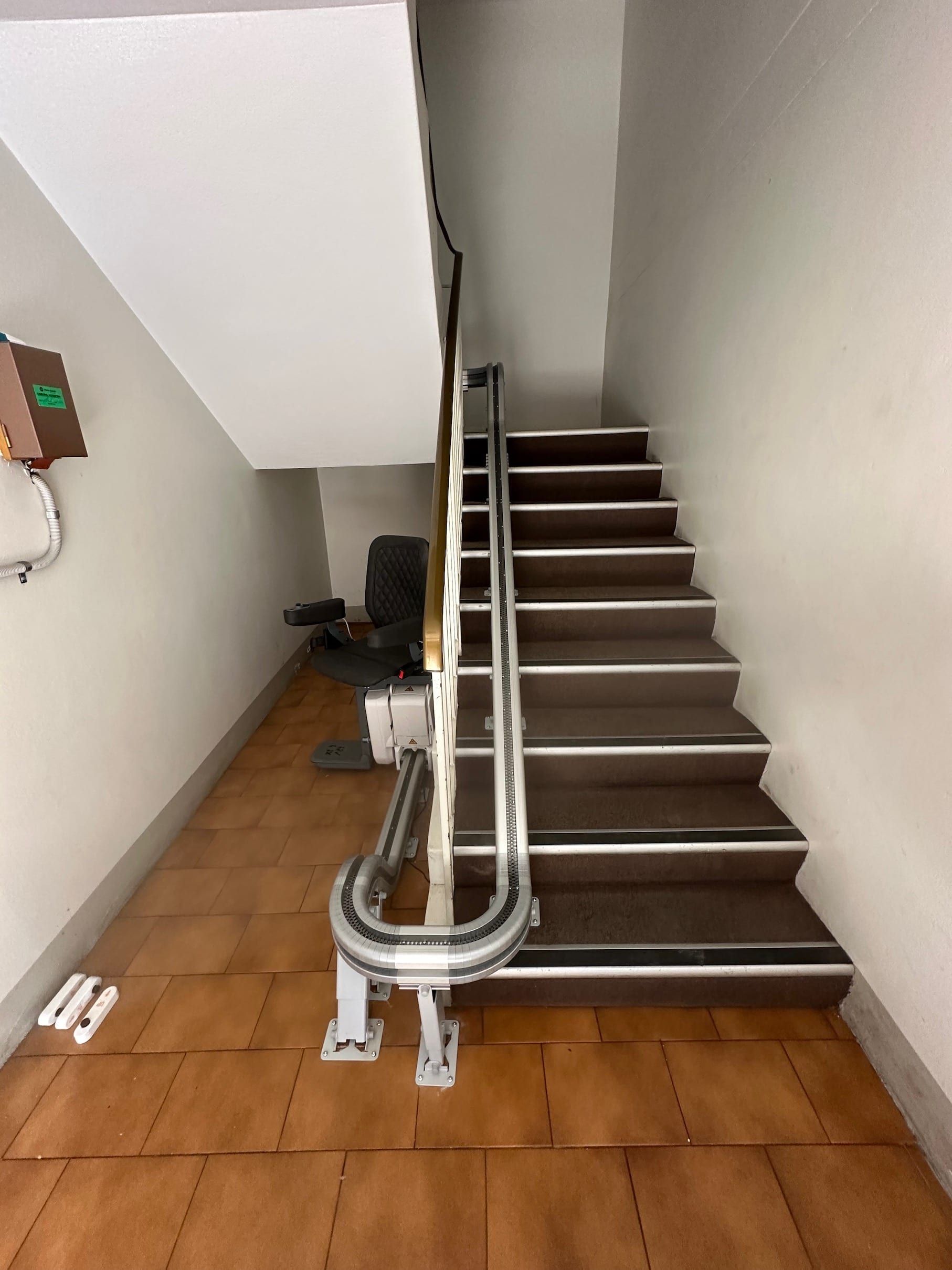 Curved, silver curtain track mounted on wall, corner bend, wooden floor.