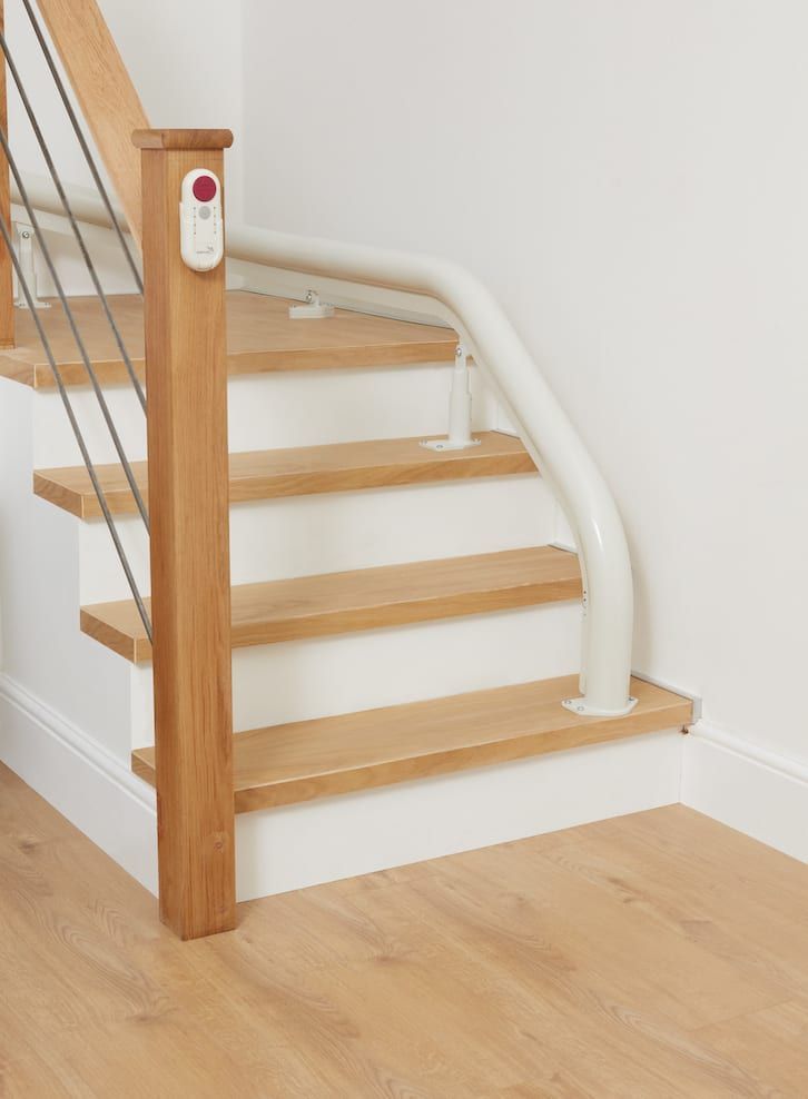 Staircase with wooden steps and a white handrail for accessibility. A remote control is on a wooden post.