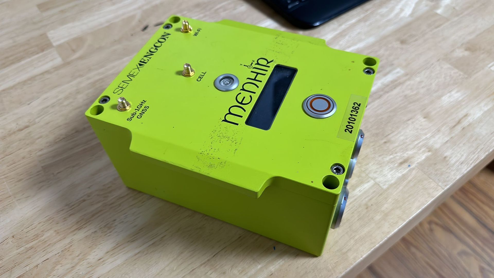 Auf einem Holztisch steht ein grünes elektronisches Gerät.