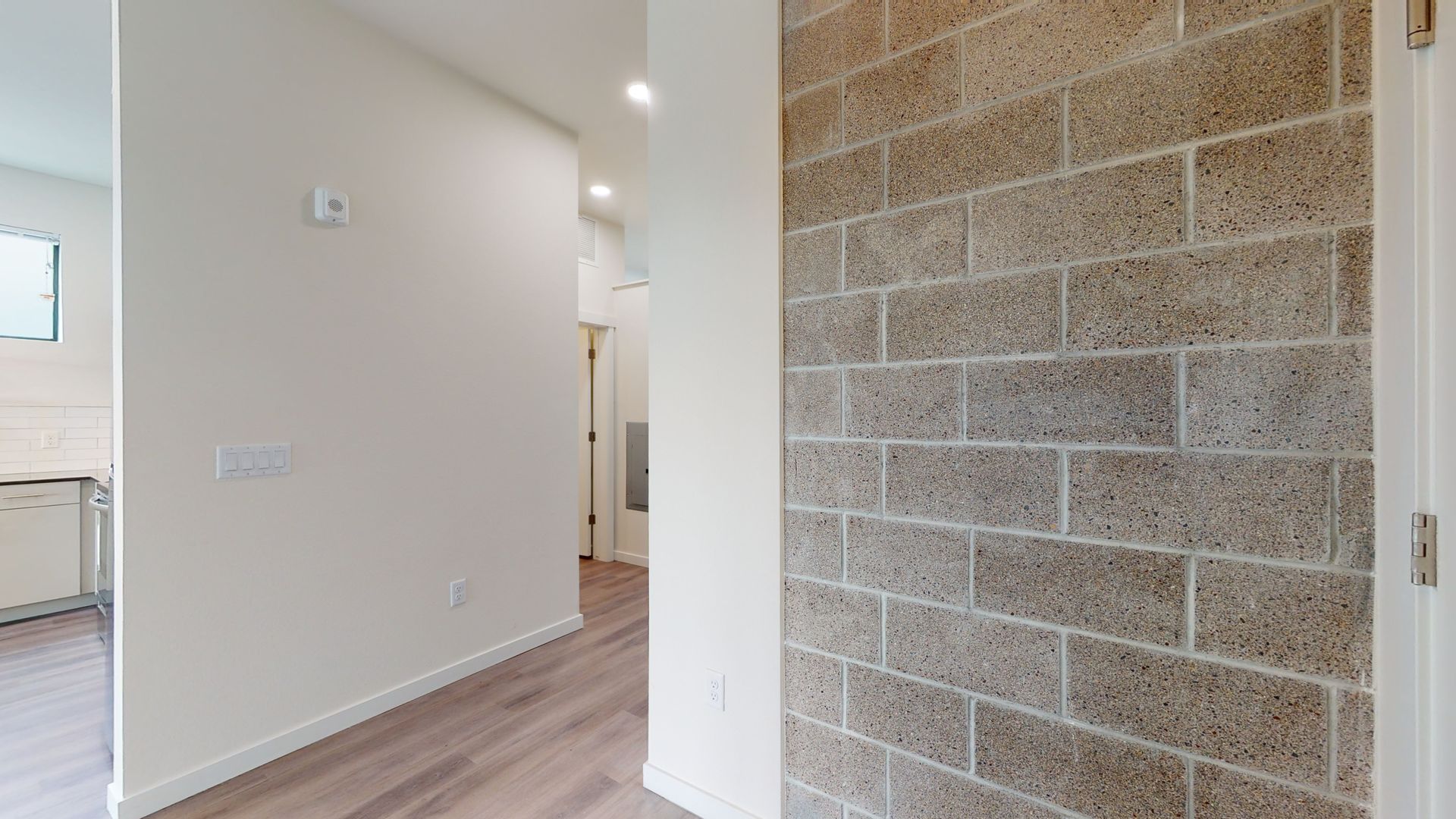 Hallway with exposed brick wall and light wooden floors.