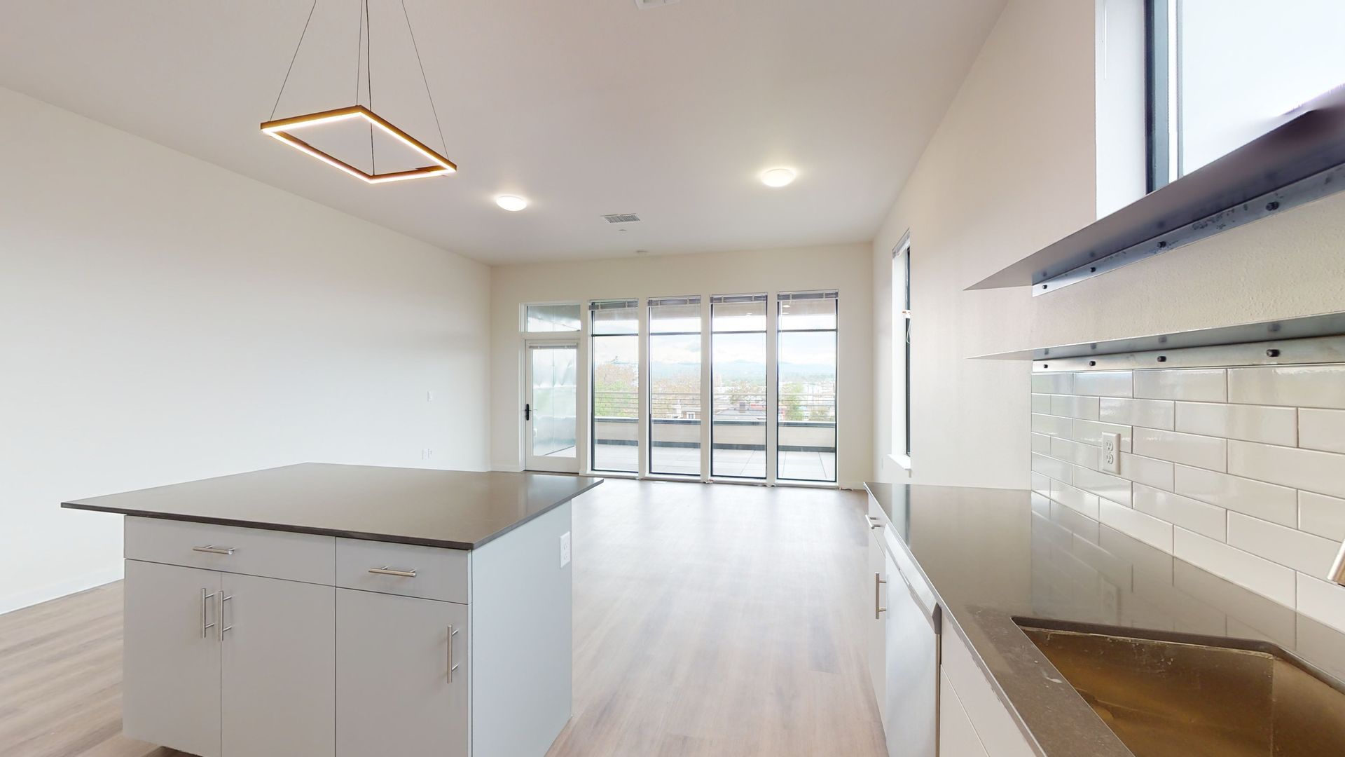 Modern, minimalist kitchen with island, white cabinets, and large folding glass doors.