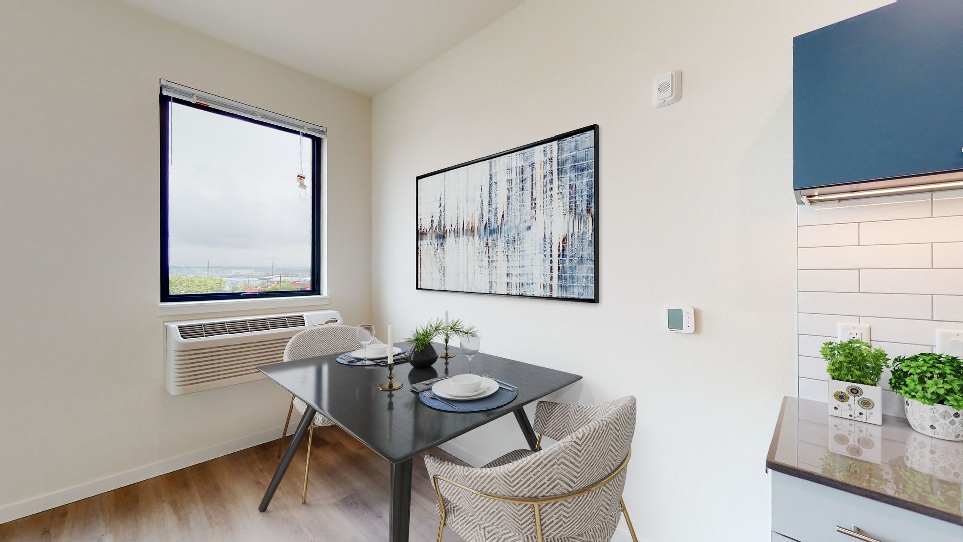 Small dining area with a table, chairs, and artwork. Window offers an outdoor view.